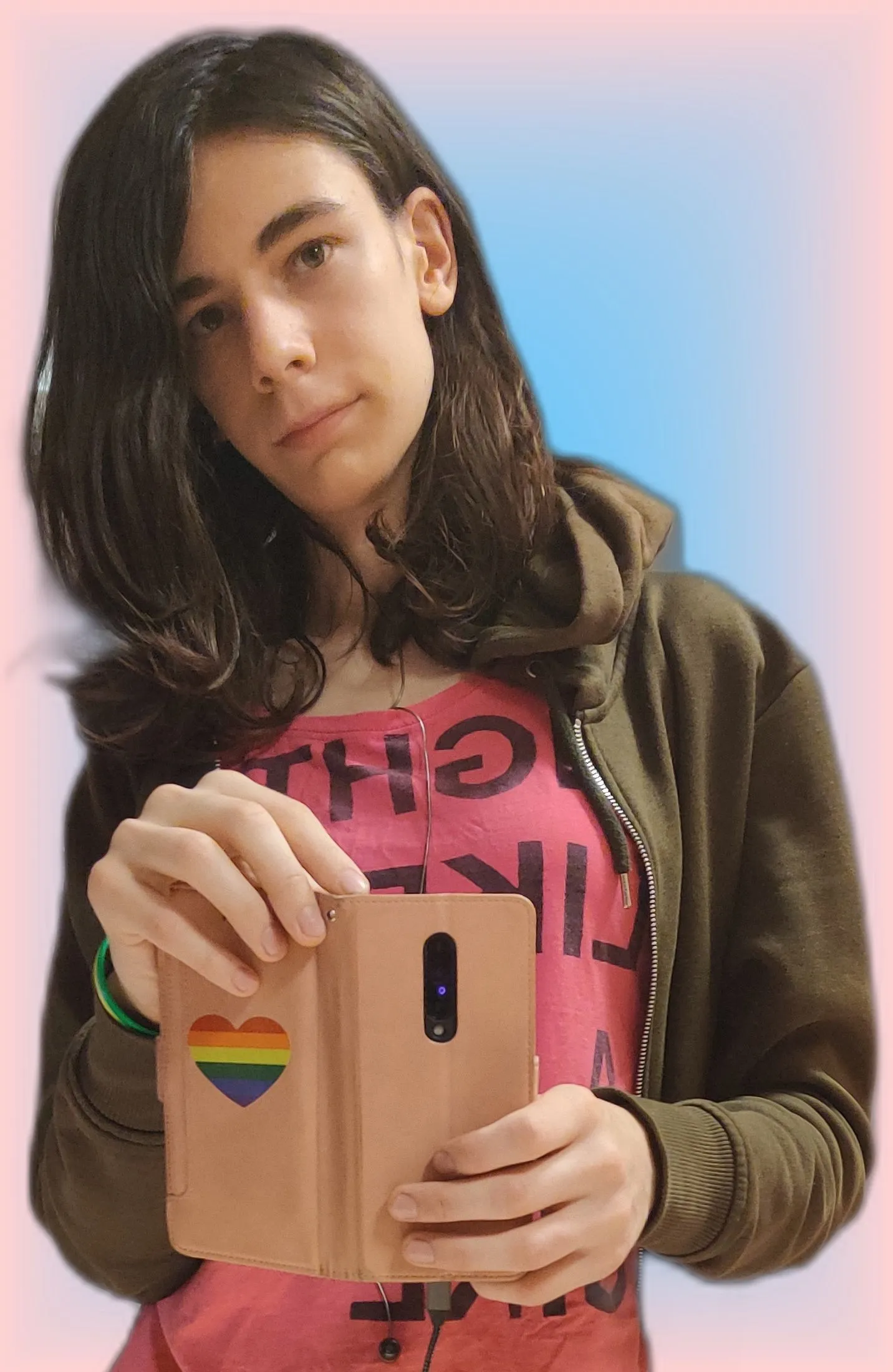 Photo of me holding my phone with a rainbow heart on it. I'm wearing a T-shirt that says 'fight like a girl'